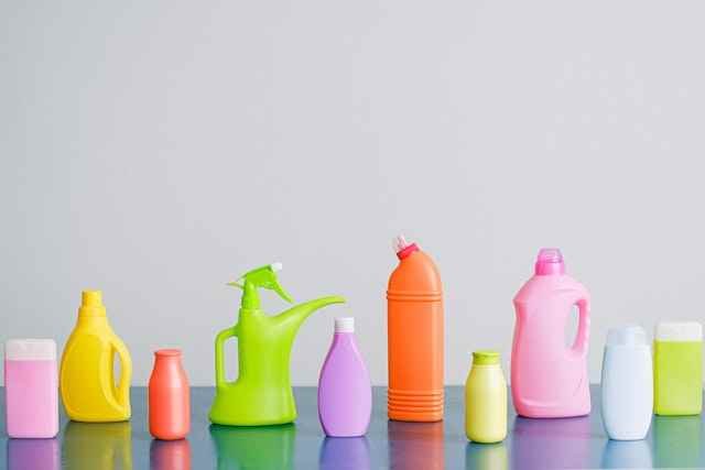 Many liquid detergent bottles on a shelf in a bathroom