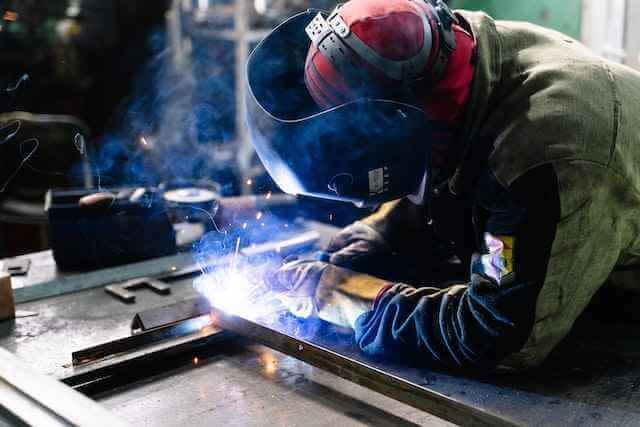 A welder is Welding something with helmet on