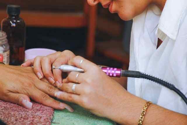 A nail technician doin nail treatment of a client